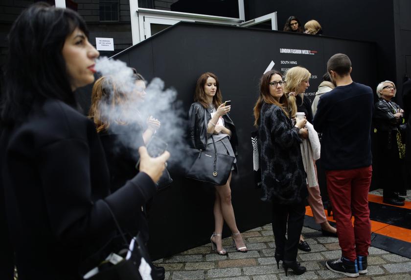 A woman blows smoke from a cigarette as people queue for the Holly Fulton show during London Fashion Week. u00e2u20acu201d Reuters pic