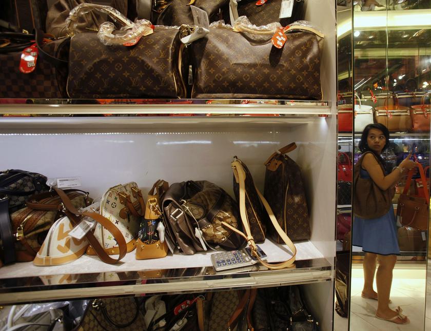 A customer, reflected in a mirror, chooses a luxury handbag at a Milan Station outlet in Hong Kong September 2, 2013. u00e2u20acu201c Reuters pic