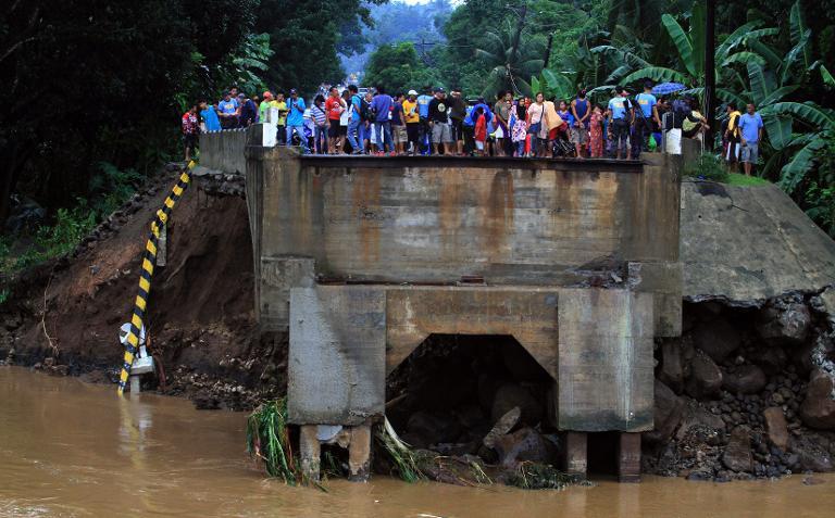 Residents stand on the edge of a bridge destroyed by flooding in Linamon town on the southern island of Mindanao on January 14, 2014. u00e2u20acu201d AFP pic
