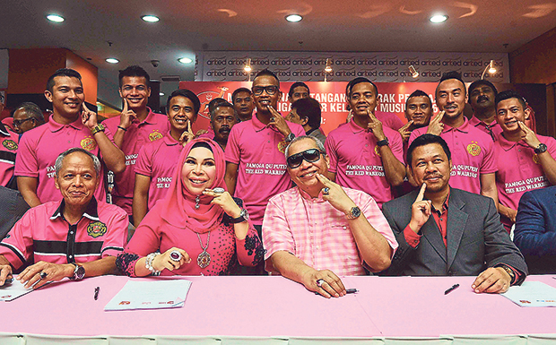 Hasmiza Othman or Datuk Seri Vida and members of the Kelantan Football Association (Kafa) striking the trademark Qu Puteh pose at the signing of the RM16 million sponsorship deal. Next to her in pink is Kafa president Tan Sri Annuar Musa.  — Picture by BERNAMA