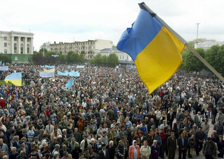 A Ukrainian national flag with a mourning ribbon attached above thousands Crimean Tartars during their  rally in Crimea. u00e2u20acu201d AFP pic