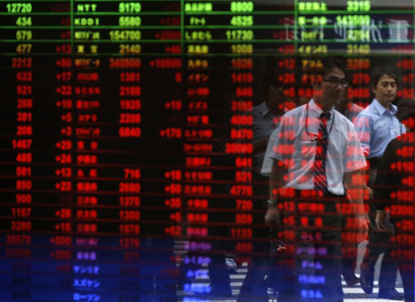 Passersby are reflected on a window showing a stock quotation board at a brokerage in Tokyo. u00e2u20acu201d Reuters pic