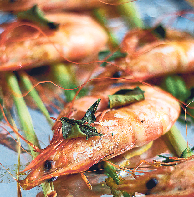 To grill the marinated prawns, rest them on halved stalks of lemongrass and top with kaffir leaves