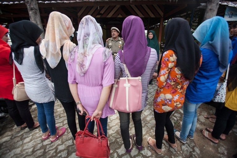 An Indonesian Muslim official (C-brown uniform) speaks to female students caught wearing tight trousers which is against shariah-law in Banda Aceh on September 3, 2013