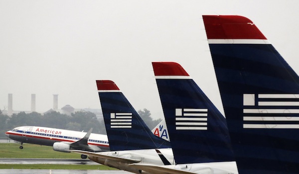 An American Airlines jet takes off while US Airways jets are lined up at Reagan National Airport in Washington in this July 12, 2013 file photo. u00e2u20acu201d Reuters pic
