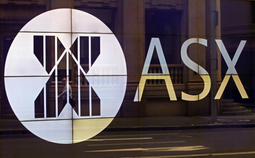 An office worker walks past the board of the Australian Securities Exchange building displaying its logo in central Sydney April 5, 2013. REUTERS