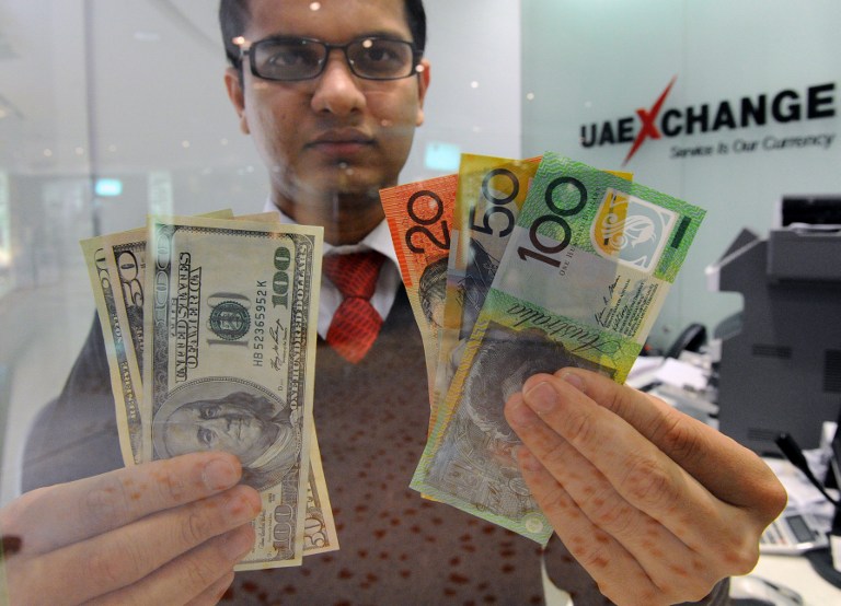 A money changer displays a selection of US dollars (left) and Australian polymer notes in Sydney. u00e2u20acu201c AFP pic
