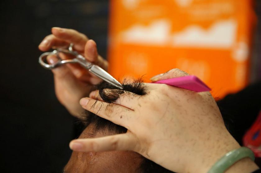 Azmina says that she does not use gloves to cut hair for the homeless because the human touch is important.