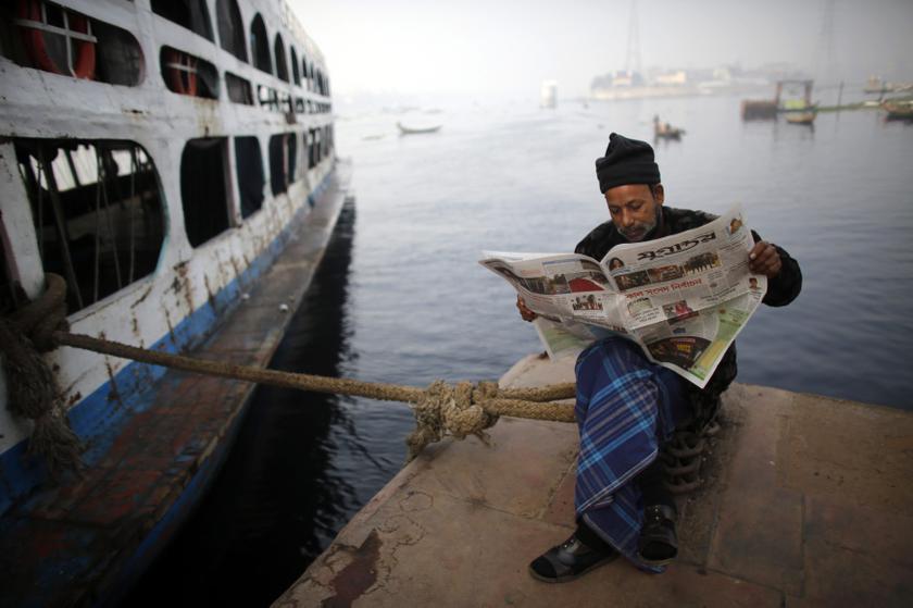  A man reads a local newspaper containing news about Sunday's election by the Buriganga River during a strike in Dhaka January 4, 2014