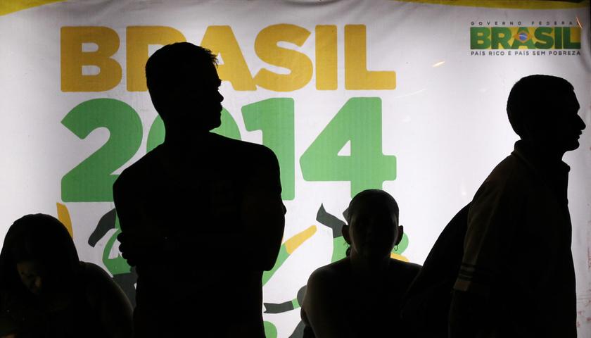 People are silhouetted in front of an advertisement of the Brazil 2014 FIFA Soccer World Cup as they wait for a bus in Recife June 21, 2013. u00e2u20acu201d Reuters pic