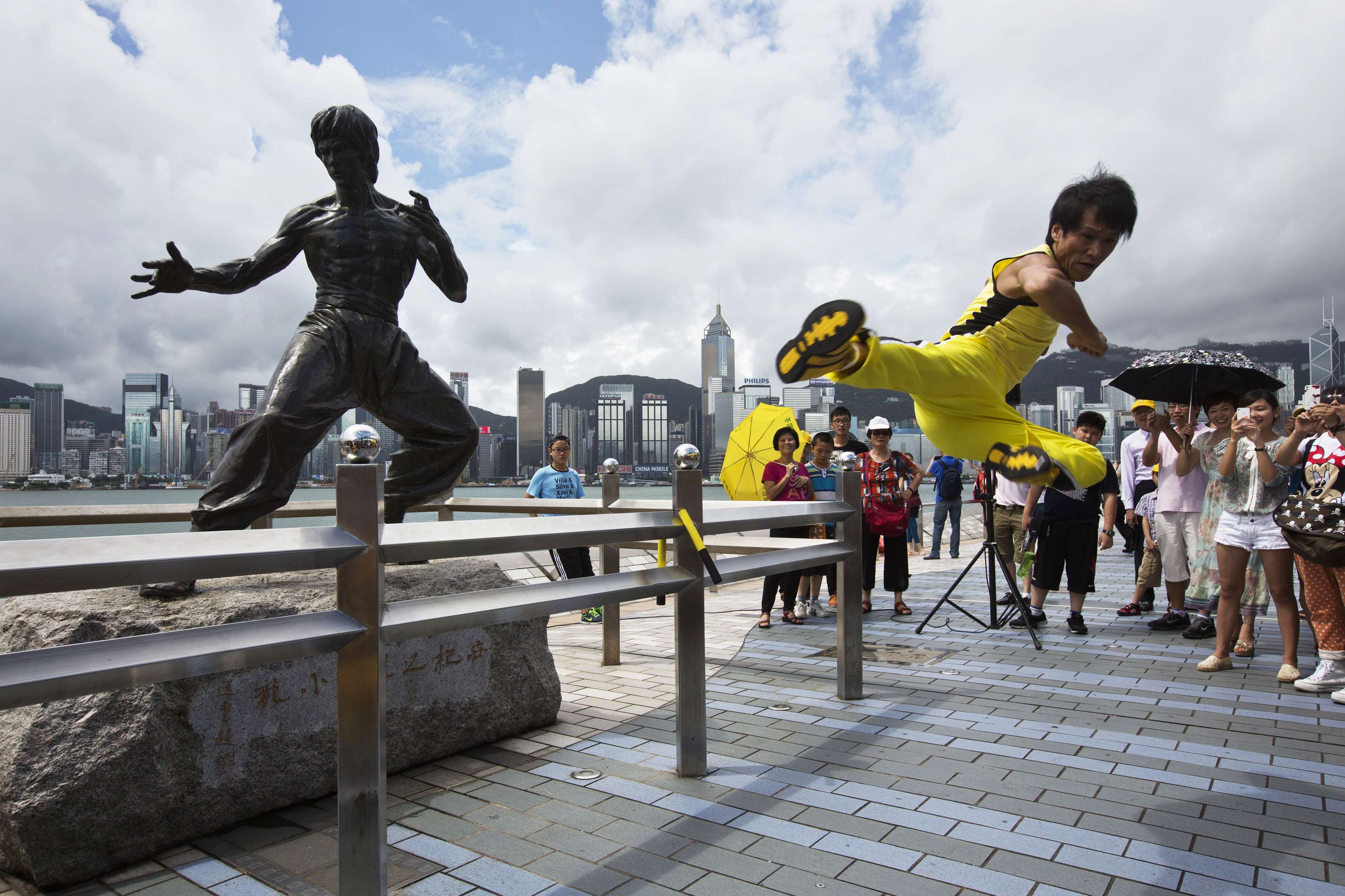 Chinese actor Mei Zhiyong performs a flying kick in front of a bronze statue of kung fu legend Bruce Lee on the waterfront of Hong Kong July 20, 2013. u00e2u20acu201d Reuters pic