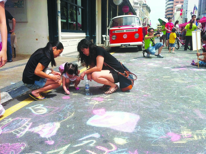 Visitors having fun drawing on the tarred road with chalk.