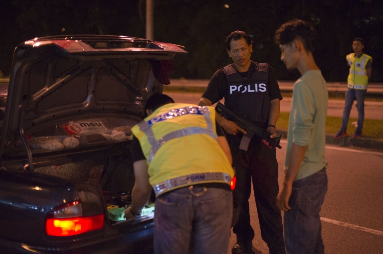 This picture taken in the early hours of August 21, 2013 shows Malaysian policemen checking a vehicle at a roadblock during an operation called 'Op Cantas Khas' in Kuala Lumpur. u00e2u20acu201c AFP pic