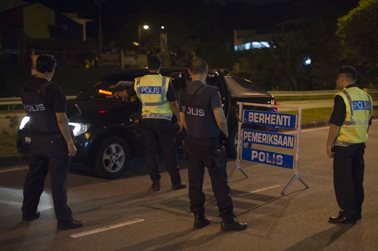 This picture taken in the early hours of August 21, 2013 shows Malaysian policemen checking a vehicle at a roadblock during an operation called 'Op Cantas Khas' in Kuala Lumpur. u00e2u20acu201c AFP pic