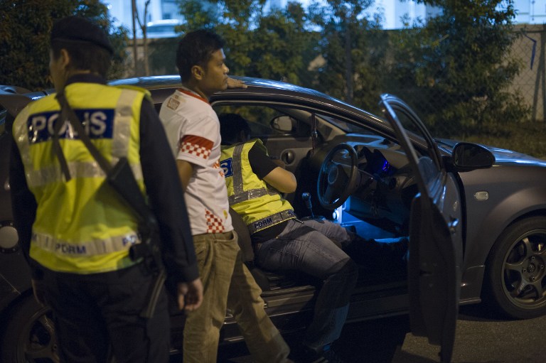 This picture taken in the early hours of August 21, 2013 shows Malaysian policemen checking a vehicle at a roadblock during an operation called 'Op Cantas Khas' in Kuala Lumpur. u00e2u20acu201c AFP pic