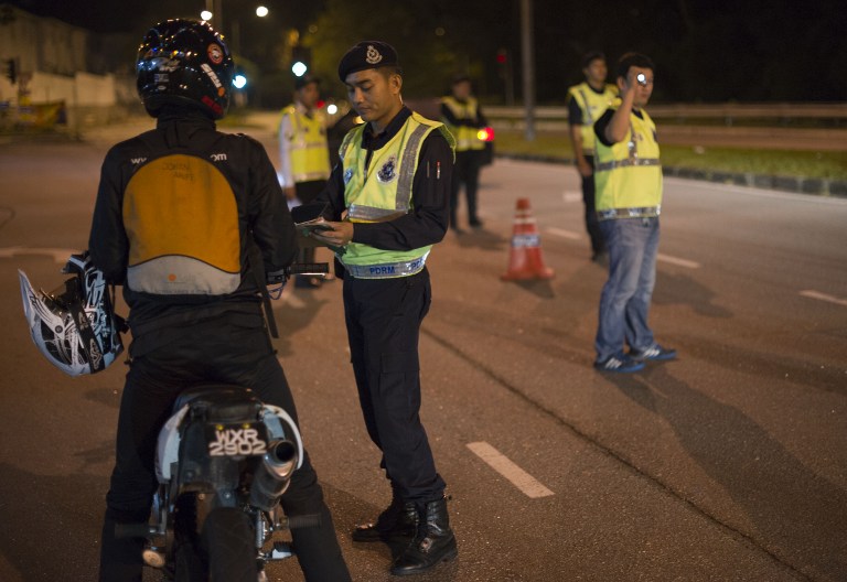 This picture taken in the early hours of August 21, 2013 shows Malaysian policemen checking a vehicle at a roadblock during an operation called 'Op Cantas Khas' in Kuala Lumpur. u00e2u20acu201c AFP pic