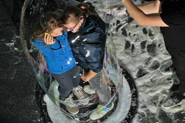 People speak on the telephone from inside a giant bubble made by professional bubblemaker Matej Kodes (right) during the Guinness Book of records attempt to set a new record at a shopping mall in Olomouc, Czech Republic on November 16, 2013. u00e2u20acu201d AFP pic