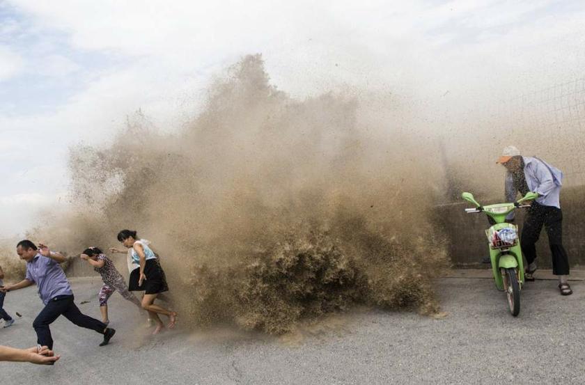 People run as waves from a tidal bore surge past a barrier on the banks of the Qiantang River, under the influence of Typhoon Trami, in Hangzhou, Zhejiang province, China on August 23, 2013. u00e2u20acu201d Reuters pic