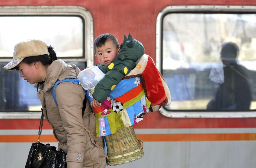 A child is carried in a basket on the back of a woman as they board a train at a railway station in Nanjing, Jiangsu province January 23, 2014. About 3.62 billion trips will be made during the 40-day Spring Festival travel rush.u00e2u20acu201d Reuters pic