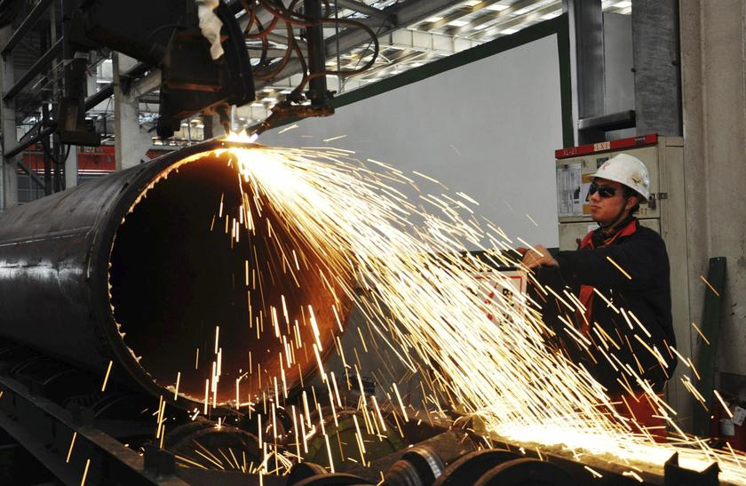 A worker operates a machine to cut a pipeline at a factory in Qingdao, Shandong province November 29, 2013. u00e2u20acu201d Reuters pic