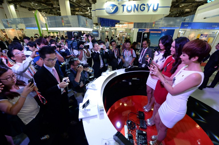 Visitors take pictures of promoters (right) displaying Huawei's Ascend P6 phone, billed as the world's thinnest smartphone, at the CommunicAsia telecom and broadcast event in Singapore on June 19, 2013. u00e2u20acu201c AFP pic