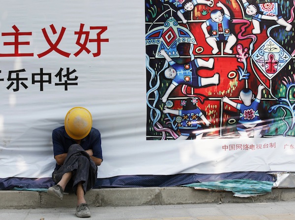 A worker takes a nap during a lunch break next to a fence of a construction site of a new apartment in Beijing September 2, 2013. u00e2u20acu201d Reuters pic