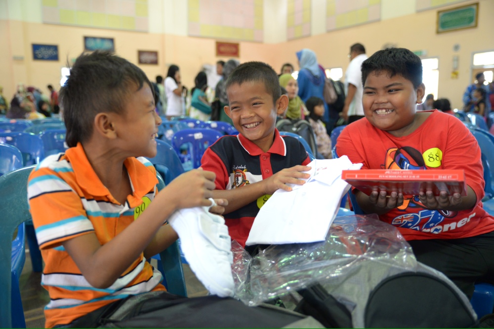 Joyous children showing each other their new back-to-school kits they received from the Tenaga Nasional Back-to-school community programme in Balik Pulau, Penang, December 23, 2013. u00e2u20acu201du00c2u00a0Picture by K.E. Ooi