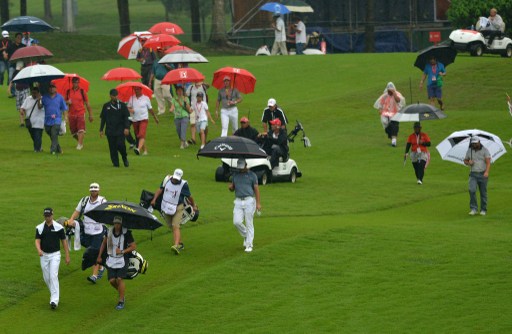 Gary Woodland (centre front), Chris Stroud (left front) and Ryan Moore (right front) on the fairway before play was suspended due to heavy rain during the final round of the CIMB Asia Pacific Classic golf tournament in Kuala Lumpur on October 27, 2013.  u00e2