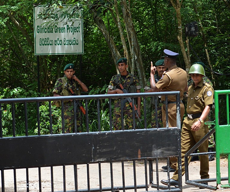 Sri Lankan police and Special Task Force commandos stand guard outside a rubber glove manufacting plant in the village of Weliweriya on August 3, 2013. u00e2u20acu201c AFP pic