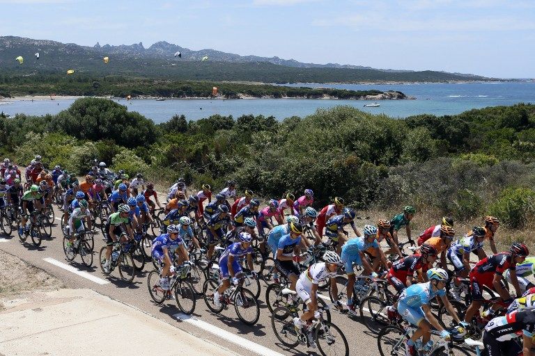 The pack rides as people pratice kitesurf along the road during the 213 km first stage of the 100th edition of the Tour de France cycling race on June 29, 2013 between Porto-Vecchio and Bastia, on the French Mediterranean Island of Corsica. 