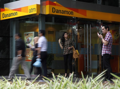 A man smokes a cigarette near a Danamon Bank ATM in Jakarta in this May 22, 2013 file picture. u00e2u20acu201d Reuters pic
