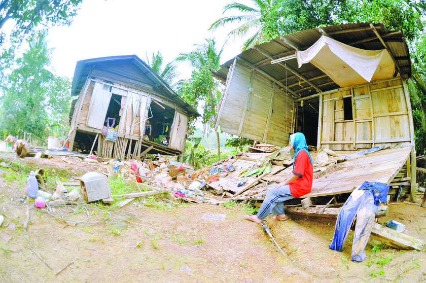 Zailati sits on one half of her house as she looks at her children in what used to be the adjoining room. u00e2u20acu201d Picture by Hadzme Mohd Jaafar