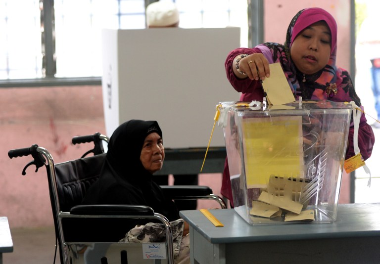 An elderly Muslim woman in a wheelchair gets a helping hand to cast her vote at the polling station in Permatang Pauh, Penang on May 5, 2013. u00e2u20acu201c AFP pic