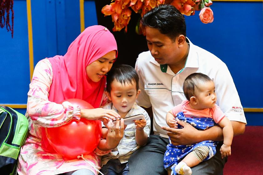 A child plays with his mother's smartphone while their family take a breather in a shopping mall in Kuala Lumpur. u00e2u20acu201d Picture by Saw Siow Feng