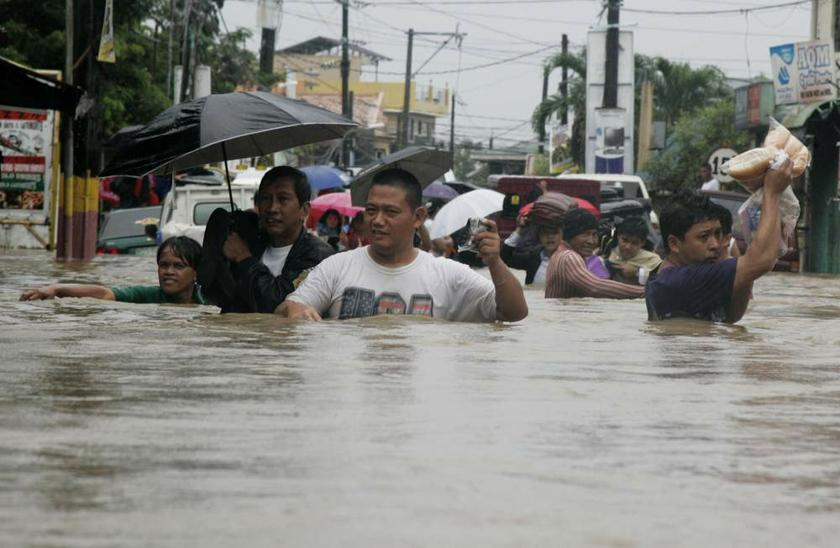 Residents wade through floodwaters brought by monsoon rain, intensified by tropical storm Trami, in Kawit town, south of Manila on August 19, 2013. u00e2u20acu201d Reuters pic