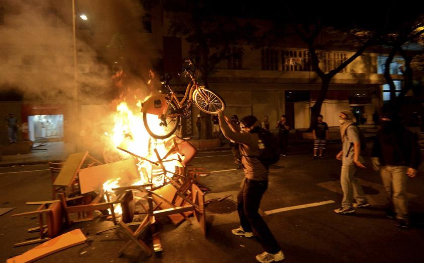 An anti-government protester throws a bike onto a fire during a clash with riot police after a protest supporting a teachers' strike in Rio de Janeiro October 15, 2013 Reuters pic