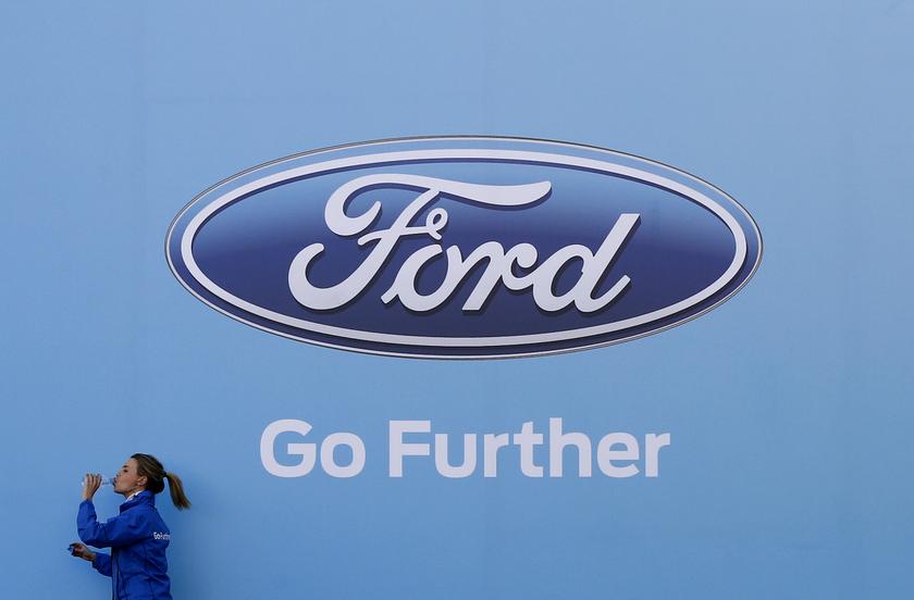 A woman has a drink as she walks past a logo of carmaker Ford at the entrance to a media event for the launch of a concept car in Sydney August 13, 2013. u00e2u20acu201d Reuters pic