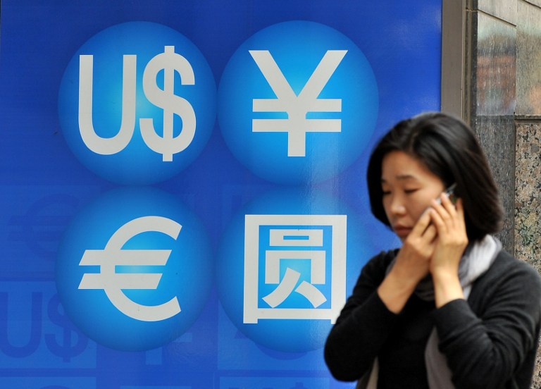 File photo of a woman walking past a money exchange sign in Seoul. u00e2u20acu201d AFP pic