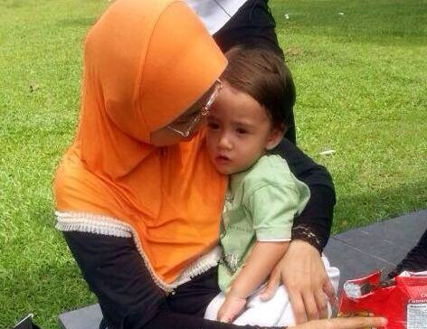 Freddie is held by an unidentified woman after he was found unhurt at Lake Titiwangsa in Kuala Lumpur.