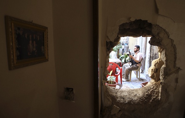 A Free Syrian Army fighter holding his weapon is pictured through a hole in the wall in the old city of Aleppo, September 3, 2013. u00e2u20acu201d Reuters pic