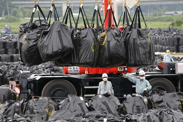 Workers move waste containing radiated soil, leaves and debris from the decontamination operation at a storage site in Naraha town, in Fukushima prefecture, August 24, 2013. u00e2u20acu201d Reuters pic