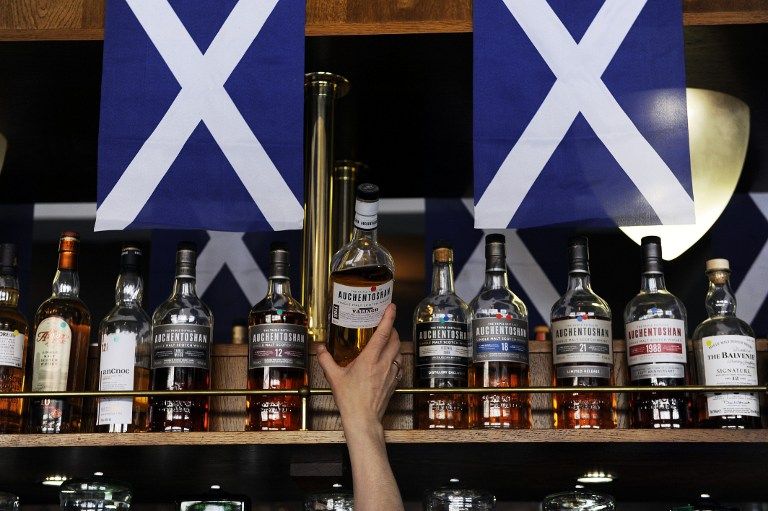 A barman lifts a bottle of Scotch whisky from a shelf in the Deoch An Dorus pub in the Partick area of Glasgow on September 17, 2013. u00e2u20acu2022 AFP pic
