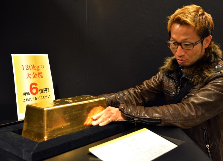 A visitor tries to lift a 120kg gold bar, displayed at the ,Gold Expo, exhibition at Tokyo's Matsuzakaya department store on April 3, 2013. 