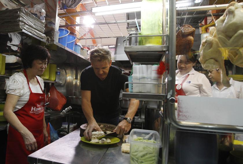 British celebrity chef Gordon Ramsay plates pieces of chicken as he prepares a chicken rice dish with Foo Kui Lian (left) of Tian Tian Hainanese Chicken Rice stall at a food center in Singapore July 5, 2013. u00e2u20acu201d Reuters pic