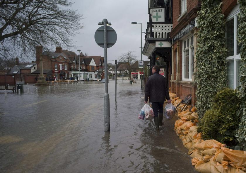 A man carries bags full of groceries through the flooded central square in the village of Datchet in Berkshire, southern England February 12, 2014. u00e2u20acu201d Reuters pic