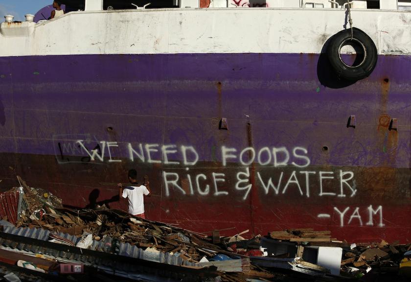 A man gathers wood from debris to build his make-shift home in front a ship, with words painted on its hull by a typhoon survivor, in Tacloban, November 15, 2013. u00e2u20acu201d Reuters pic