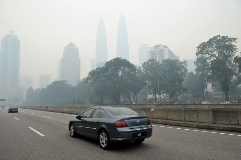 Motorists drive as haze shrouds the landmark Petronas Twins Towers in Kuala Lumpur on June 23, 2013. The thick smog brought on by forest fires in Indonesia has choked parts of Malaysia. u00e2u20acu201d AFP pic