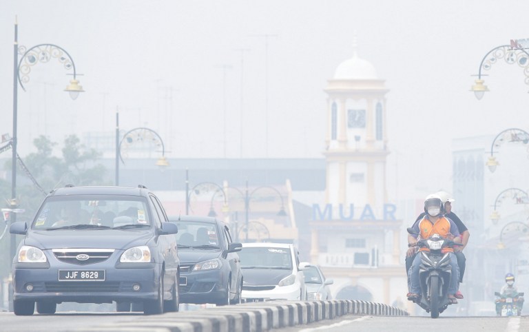 Motorists drive as haze covers Muar on June 23, 2013. The thick smog brought on by forest fires in Indonesia has choked parts of Malaysia, prompting environment officials to push for an emergency on June 23. u00e2u20acu201d AFP pic