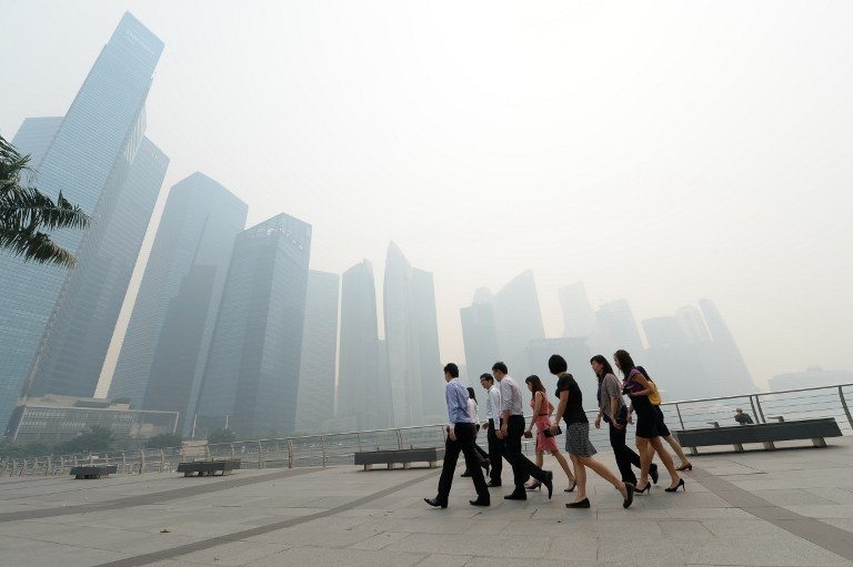 Office workers return from a lunch break in front of buildings blanketed by haze in Singapore on June 19, 2013. u00e2u20acu201d AFP pic