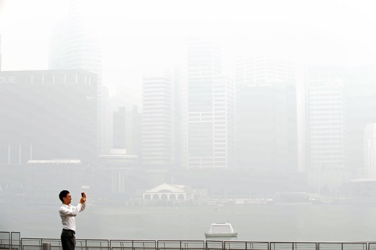 A man takes pictures of buildings blanketed by haze in Singapore on June 19, 2013. u00e2u20acu201d AFP pic